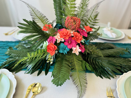 Bright colored tropical Arrangement made in a cereal bowl with monstera and cycas leaves and protea